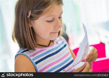 little girl embroider a cross-stitch drawing