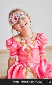 Little girl enjoying her role of princess. Adorable cute 5-6 years old girl wearing pink princess dress and tiara sitting on a floor. Little girl enjoying her role of princess. Adorable cute 5-6 years old girl wearing pink princess dress and tiara