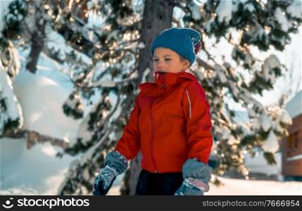 Little girl enjoying winter holidays, pretty child dressed in warm clothes having fun outdoors on backyard and playing with snow, happy winter holidays 