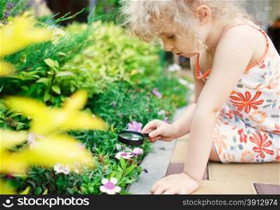 Little girl exploring nature with a magnifying glass