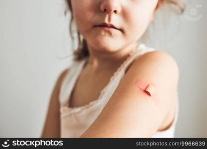 Little girl feeling pain having some side effects after vaccination. Redness, swelling, aching limbs and headache as reaction after vaccination. Getting a first injection. Healthy and medical concept