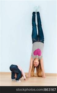 Little girl following her elder sister doing a handstand