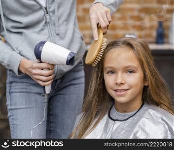 little girl getting her hair brushed dried