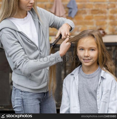 little girl getting her hair straightened by hairdresser