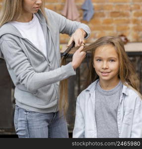 little girl getting her hair straightened by hairdresser