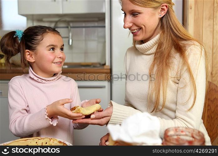 Little girl giving her mother a crepe