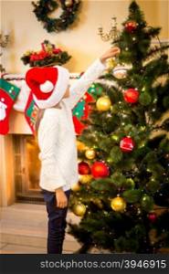 Little girl hanging decorative ball on Christmas tree
