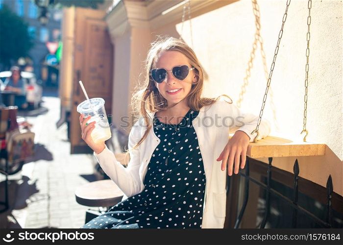 Little girl having breakfast at outdoor city cafe. Little girl at outdoor cafe on warm summer day