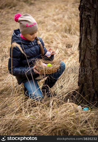 Little girl having Easter egg hunt at forest