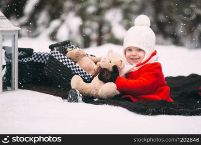 Little girl having fun on winter day. girl in red coat playing with teddy bears on plaid in winter forest.. Little girl having fun on winter day. girl in red coat playing with teddy bears on plaid in winter forest