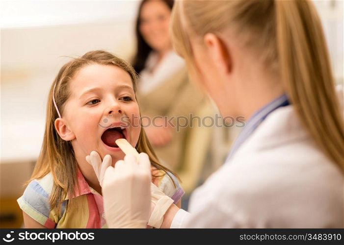 Little girl having throat examination with tongue depressor