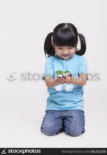 Little girl holding a seedling, studio shot