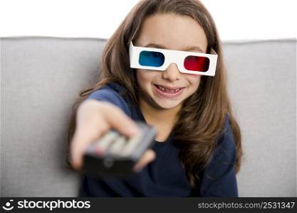 Little girl holding a TV remote control and wearing 3d glasses