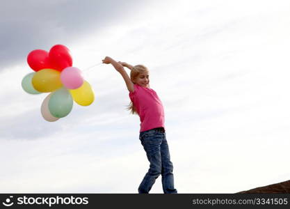 Little girl holding balloons out in the countryside