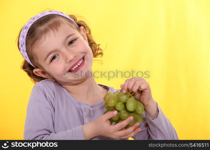 Little girl holding bunch of grapes