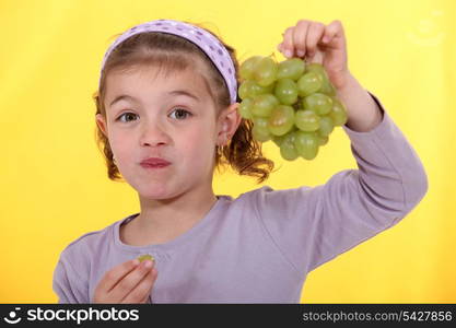 Little girl holding bunch of green grapes