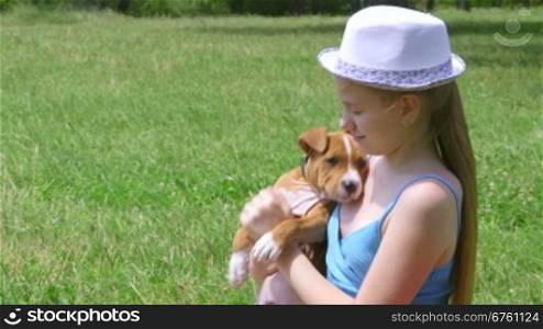 Little girl holding puppy on a grass