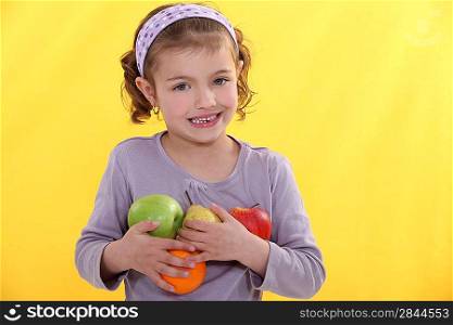 Little girl holding selection of fruit