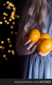 little girl holding tangerines in her hands. Christmas holidays