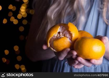 little girl holding tangerines in her hands. Christmas holidays