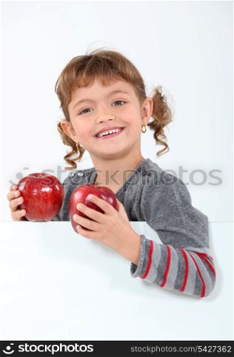 little girl holding two apples