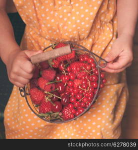 Little girl holds metal basket with summer fruits