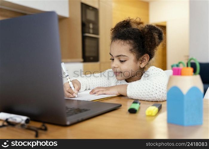 little girl home studying during online school with laptop