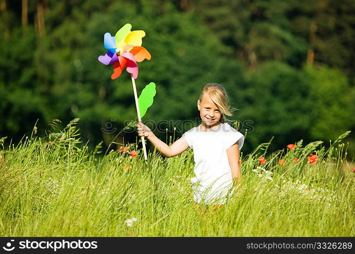 Little girl in a field playing with a colorful windmill toy