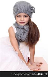 little girl in a knitted hat and gray scarf