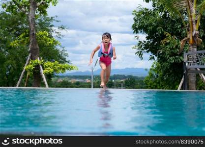 Little girl in a life jacket jumps into an outdoor swimming pool. Cute little girl playing in the pool on a sunny day. Summer lifestyle concept.