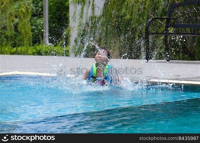 Little girl in a life jacket jumps into an outdoor swimming pool. Cute little girl playing in the pool on a sunny day. Summer lifestyle concept.