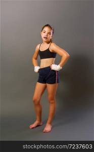 little girl in a sports tank top and shorts with hands wrapped in protective bandage is engaged in martial arts on a dark background. little mma girl