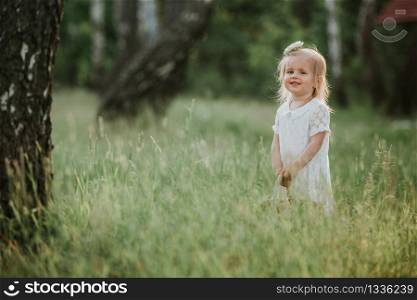 little girl in a white dress with a basket in the park. Beautiful baby girl walking in a sunny garden with a basket. Beautiful baby girl walking in a sunny garden with a basket. little girl in a white dress with a basket in the park