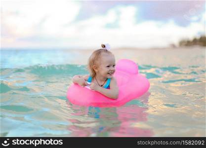 Little girl in an inflatable circle in the turquoise sea. Little girl relaxing on inflatable air mattress in the sea