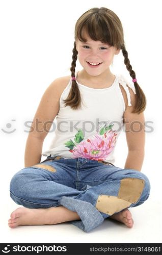 Little girl in braids sitting barefoot on white floor.