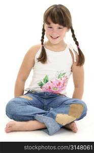 Little girl in braids sitting barefoot on white floor.
