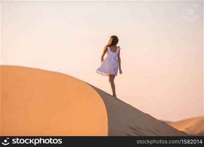 Little girl in dunes in sand desert. Girl among dunes in desert in United Arab Emirates