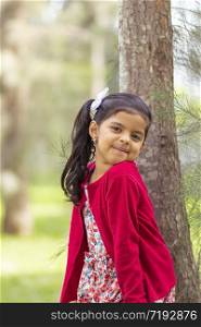 Little girl in flower dress and red sweater, very happy and smiling in the forest