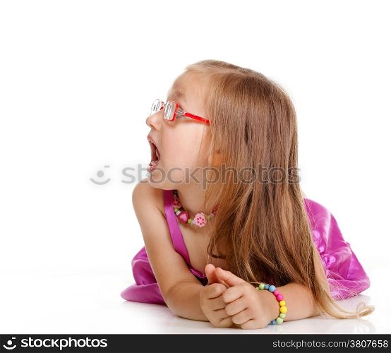 Little girl in glasses laying on floor looking to the side isolated over white
