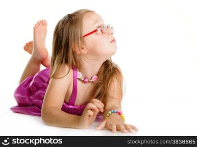 Little girl in glasses laying on floor looking to the side isolated over white