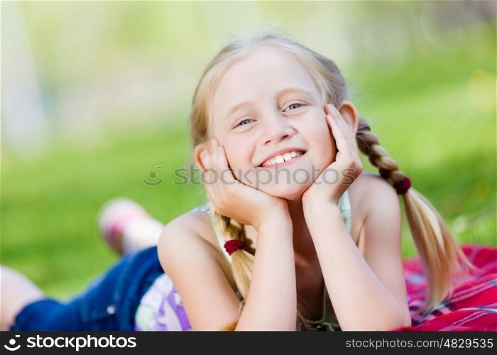Little girl in park. Image of little cute girl lying on grass in park