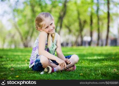 Little girl in park. Image of little cute girl sitting on grass in park