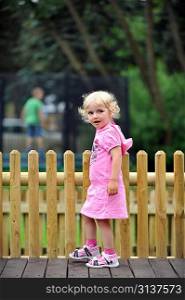 little girl in pink dress walking through park