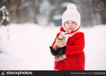 Little girl in red coat with a teddy bear having fun on winter day. girl playing in the snow.. Little girl in red coat with a teddy bear having fun on winter day. girl playing in the snow