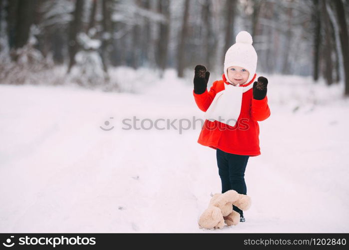 Little girl in red coat with a teddy bear having fun on winter day. girl playing in the snow.. Little girl in red coat with a teddy bear having fun on winter day. girl playing in the snow