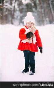 Little girl in red coat with a teddy bear having fun on winter day. girl playing in the snow.. Little girl in red coat with a teddy bear having fun on winter day. girl playing in the snow