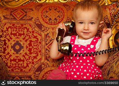 Little girl in red dress talking vintage phone. Interior in retro style. Horizontal format. Close up.