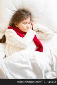 Little girl in sweater and scarf lying sleeping at bed