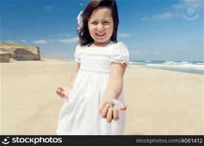 Little girl in the beach holding and playing with stones