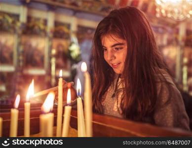 Little girl in the church on Easter, puts a candle and prays to God, enjoying happy religious holiday, good peaceful atmosphere in the holy place. Little girl in the church on Easter